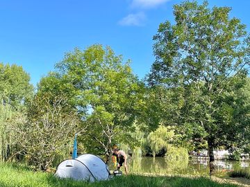 Emplacements calmes, sans électricité, situés au bord de l’étang et autre zone sur herbe pour van.