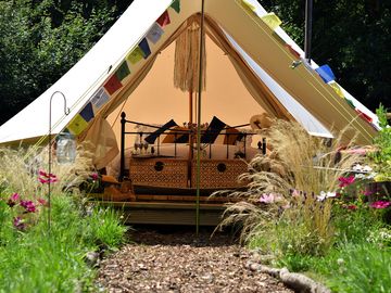 5m bell tent surrounded by wild flowers with a king size bed