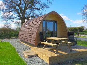 Rainbow View glamping pod with picnic table and deck chairs.