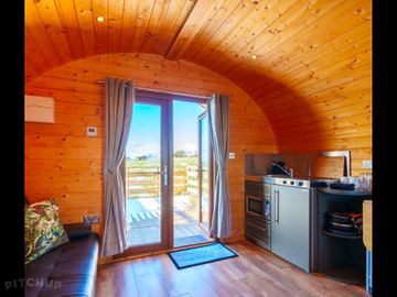 Small kitchenette with stove,sink,fridge oven and kettle. view of open doors to exterior