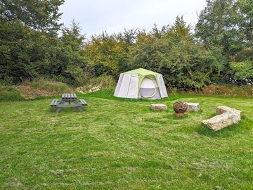 Octagonal tent with outdoor seating and firepit