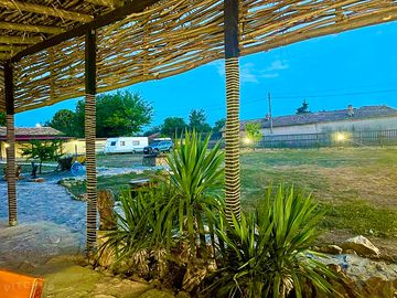 Blick von der überdachten außenterrasse mit sitzgelegenheiten auf den campingplatz am abend.