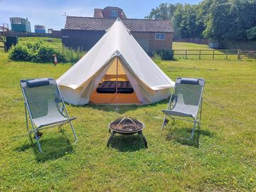 Firepit/barbecue and decking chairs outside the bell tent