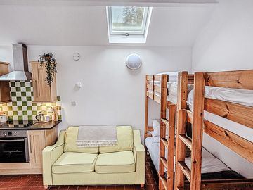 Open plan living area - equipped kitchen, sofa, tv, dining table with 4 chairs, 4 single beds