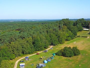 Drone image from above of Avon Tyrrell's lakeside camping and main house, with trees and blue skies