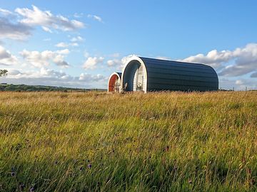 Pods set in a peaceful meadow with mountain and sea views