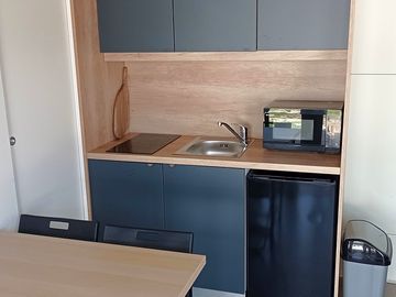 Kitchen with microwave, stove, coffee machine, fridge, cutlery and pans