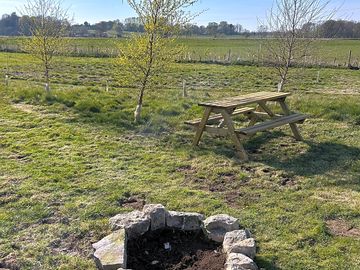 Grass pitch with picnic bench and fire pit