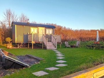 Hut in its garden with solar panels producing electricity to off set your carbon footprint 👣