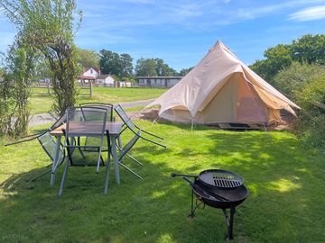 Example of luxury bell tent private space including table, chairs and fire pit