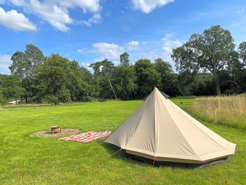Robens pre-pitched bell tent looking across the camping meadow.