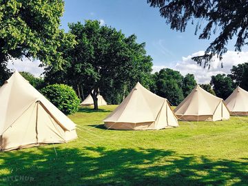 The bell tent are pitched among trees