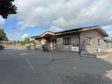 Reception outside. check for arrivals. barrier entrance. shop. park in check in lane.