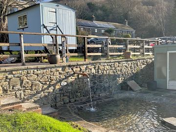 Shepherds hut and splash pool, in front of the wood and hill leading to bike park wales