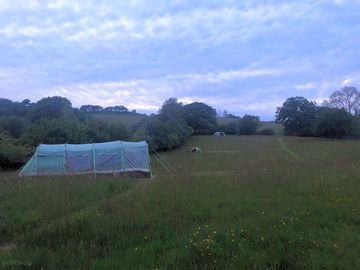View of the camping field at dusk, with tents on the bottom, middle, and top pitches