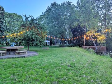Private garden with decking, picnic tables, parasol, decking over pond, and apple tree.