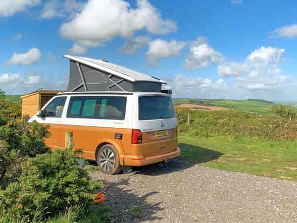 Grasbewachsener und kiesbedeckter Zelt- oder Wohnmobil-Stellplatz mit Stromanschluss