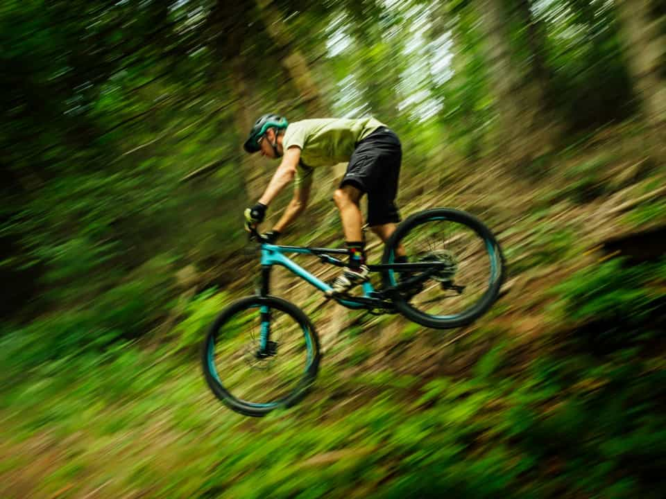 Side view of person riding mountain bike through a forest, blurred for speed