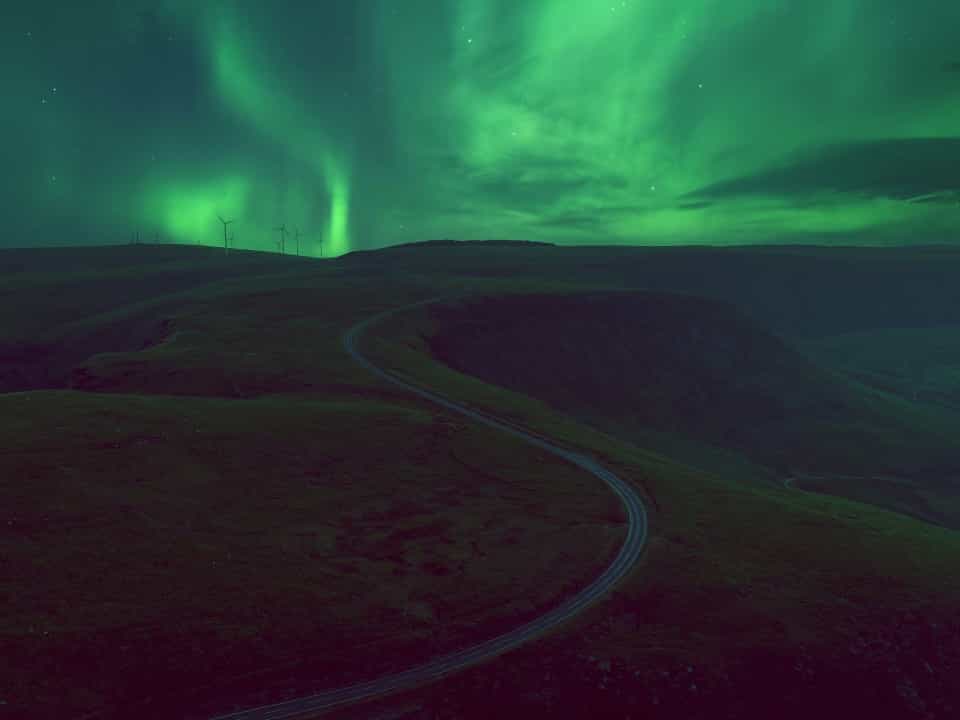 Green Northern Lights over a dark road in the Brecon Beacons