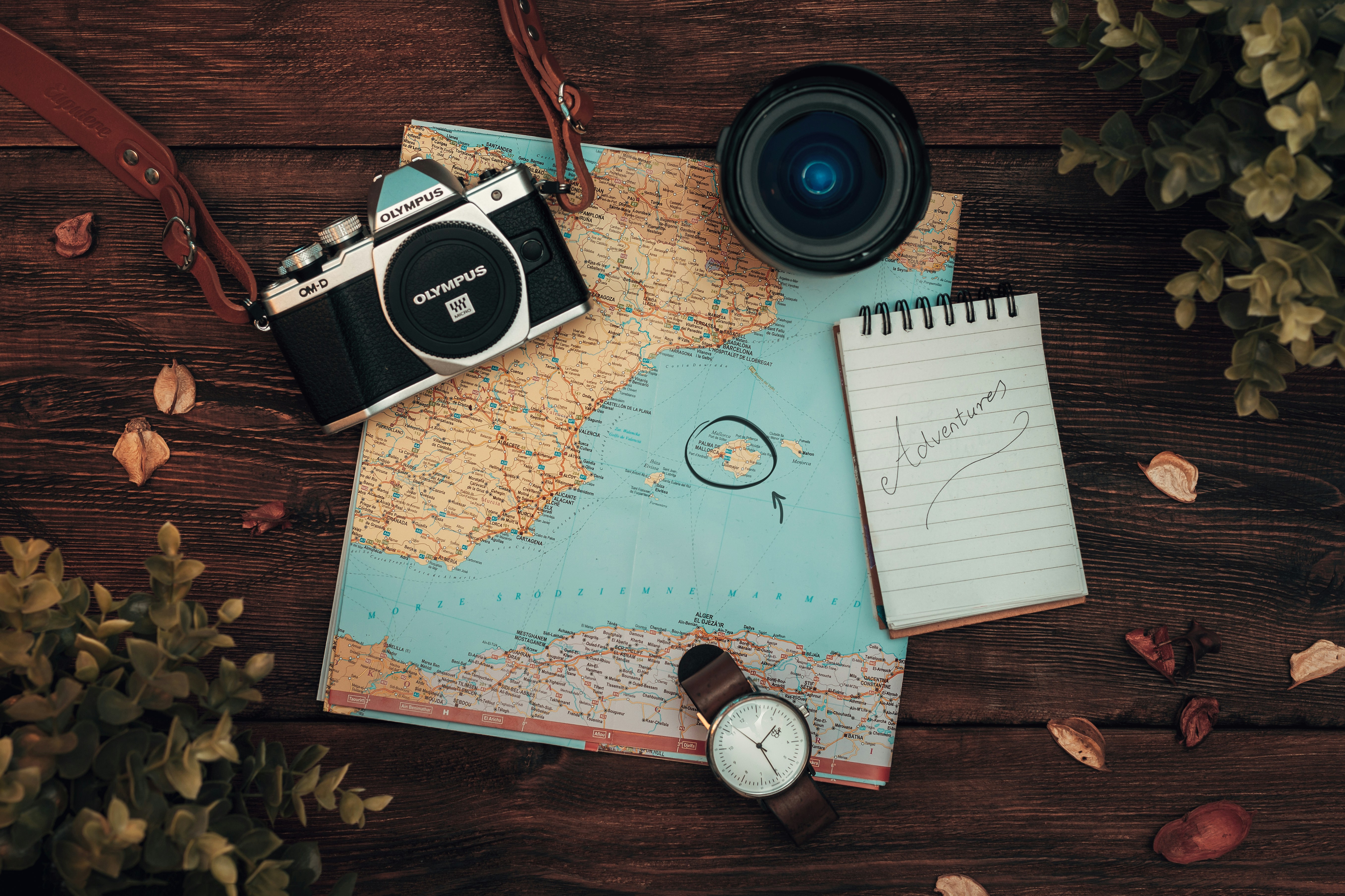 Image shows a map laid out with a compass, passport and notepad on top which reads adventures