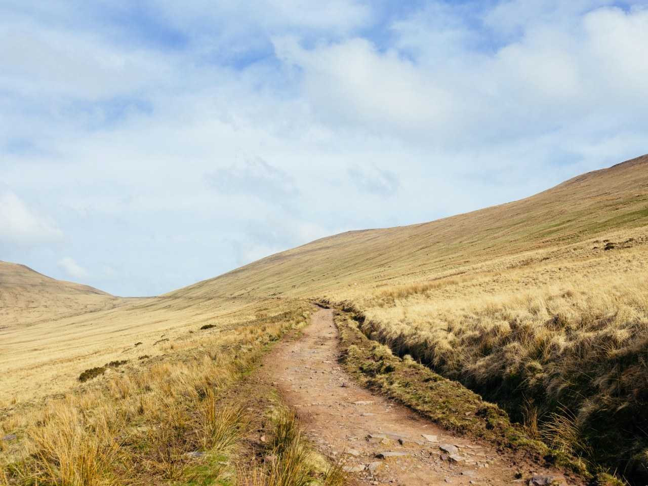 Dirt path between two hills snaking into the distance