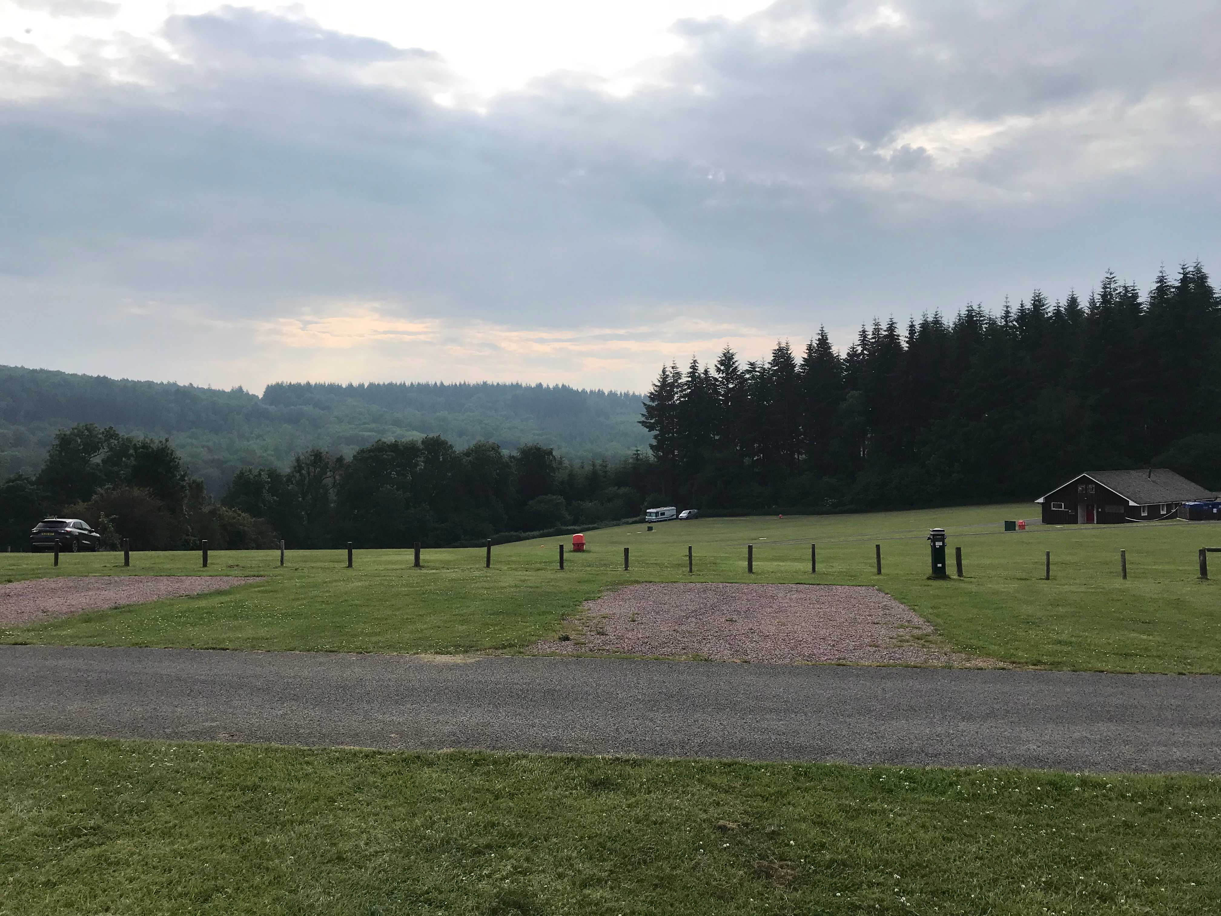 Caaravan pitches overlooking green fields and in the distance a forest