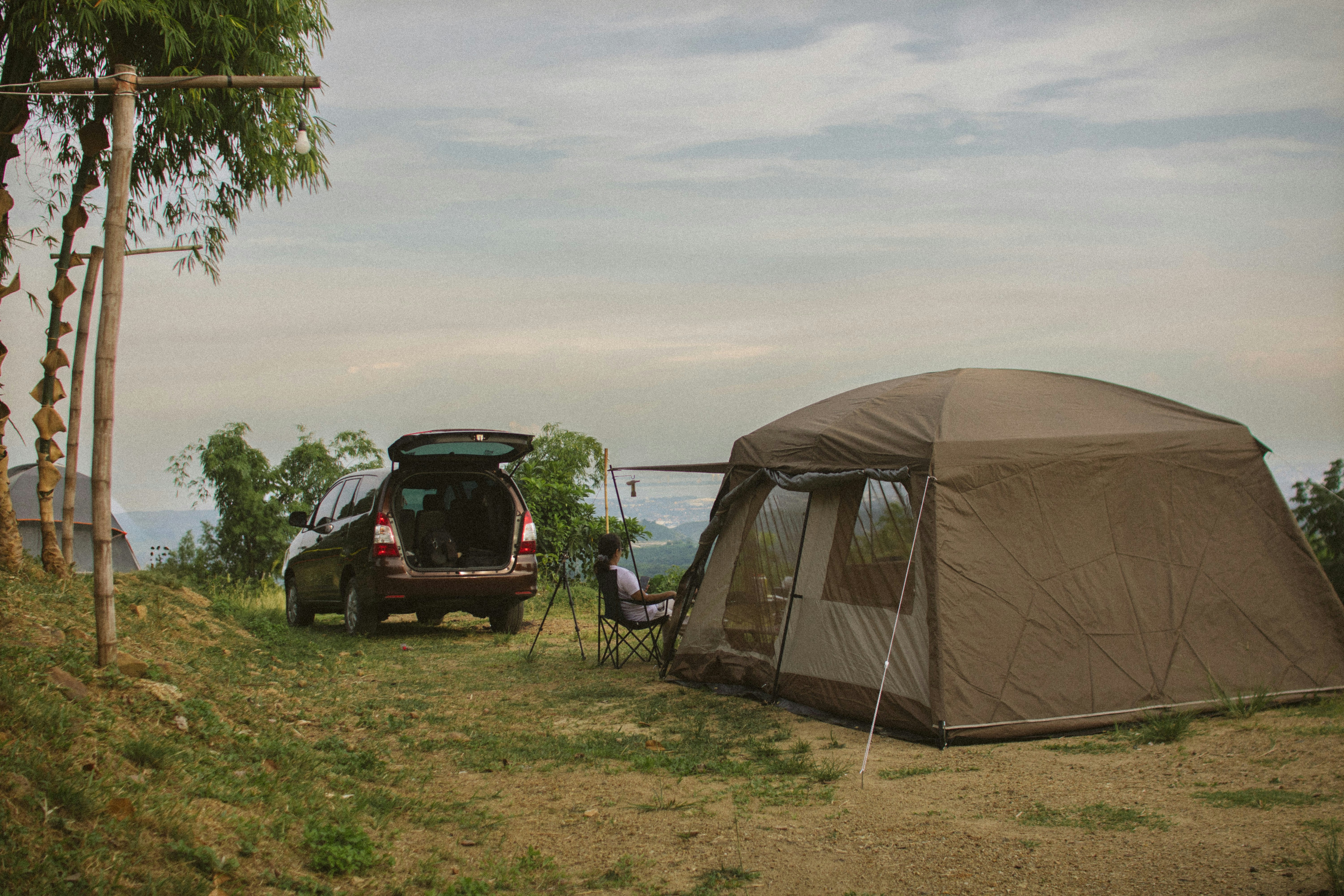 Image shows a car with its boot open next to a pitched tent 