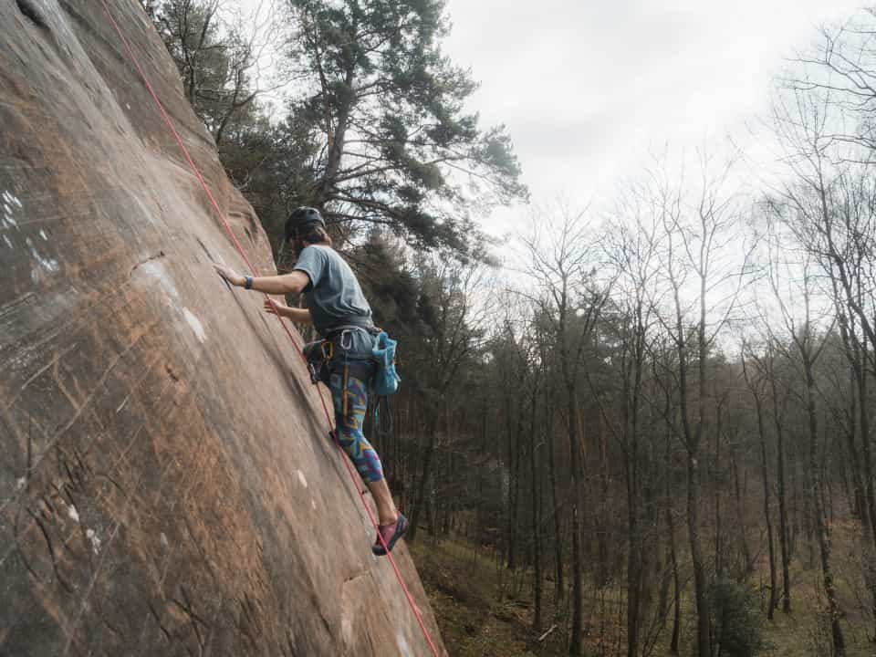 Person outdoor climbing with ropes on rocks