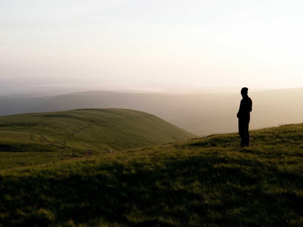 Man standing on a grassy hilltop