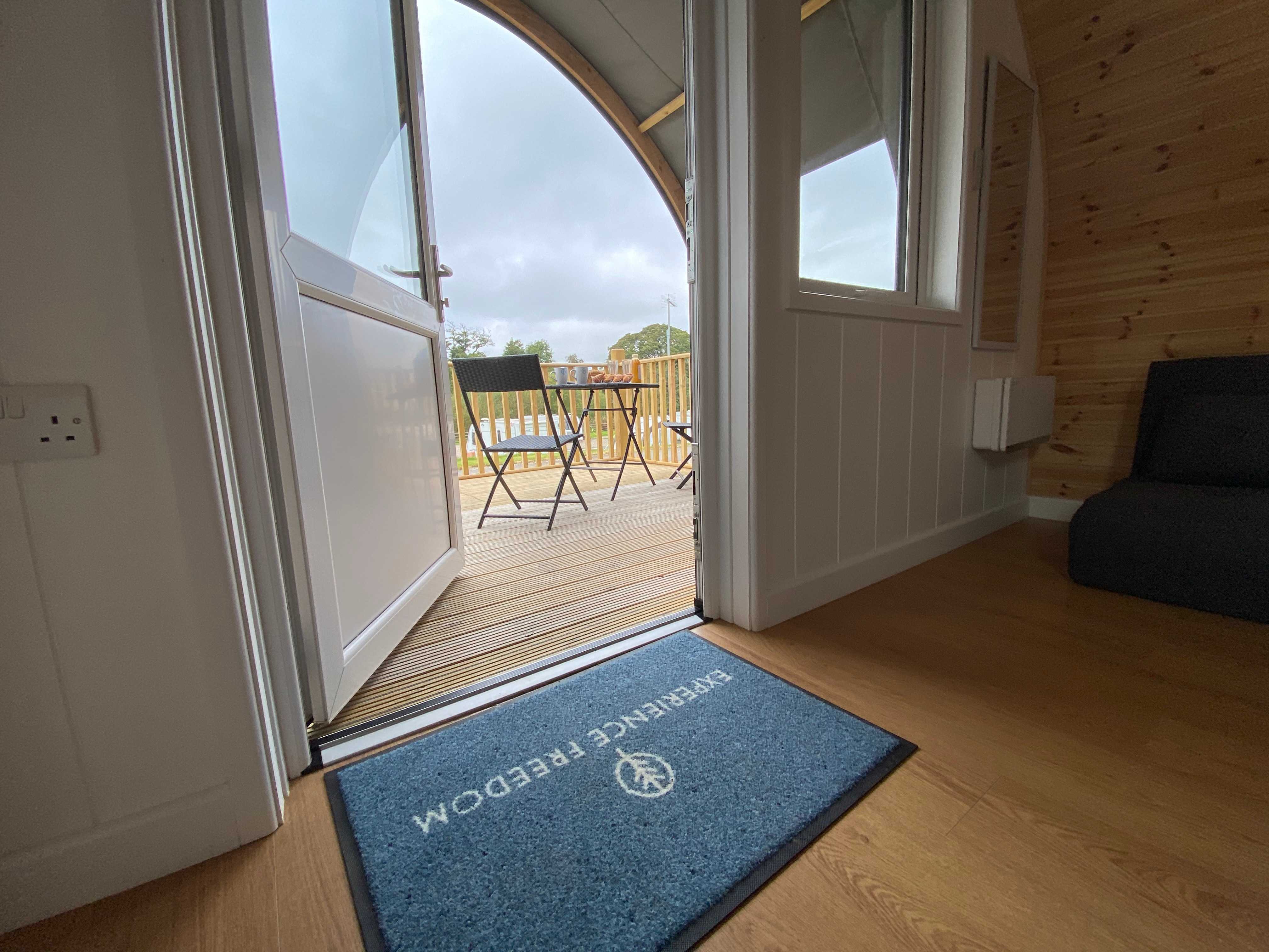 A log cabin with the door open, looking from the inside out towards the patio, showing a step free entrance