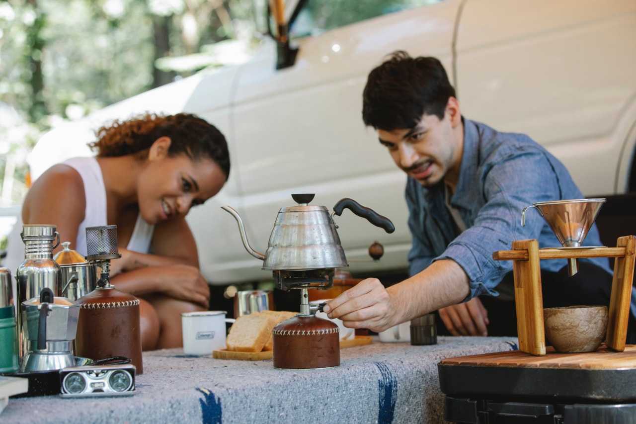 A couple use a camping stove to heat a kettle (Uriel Mont / Pexels)