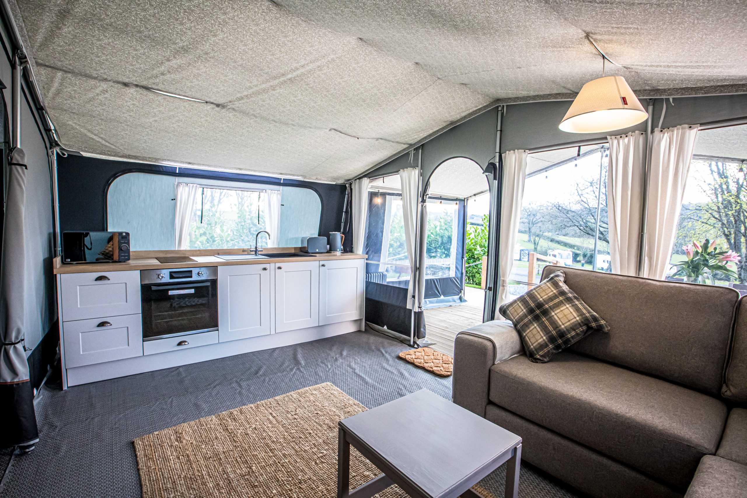 Image showing the level access entrance to a safari tent looking from the inside out, showing the corner sofa and kitchen side