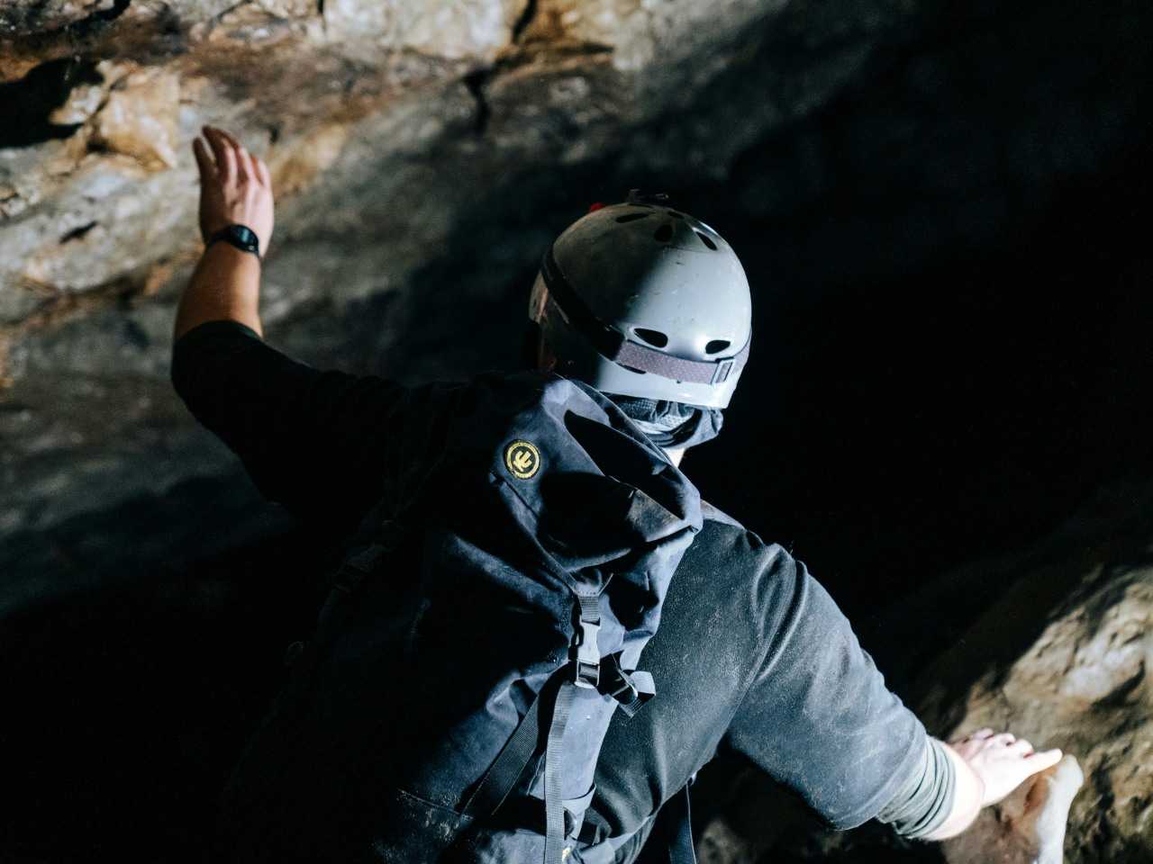 Man in cave with helmet and backpack