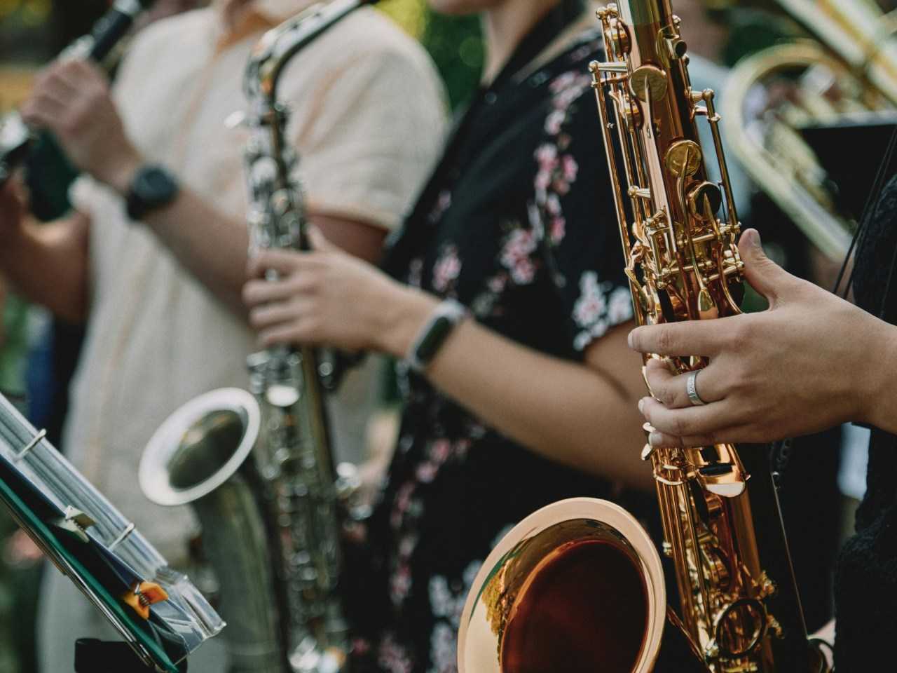 Person in black and white floral shirt playing saxophone