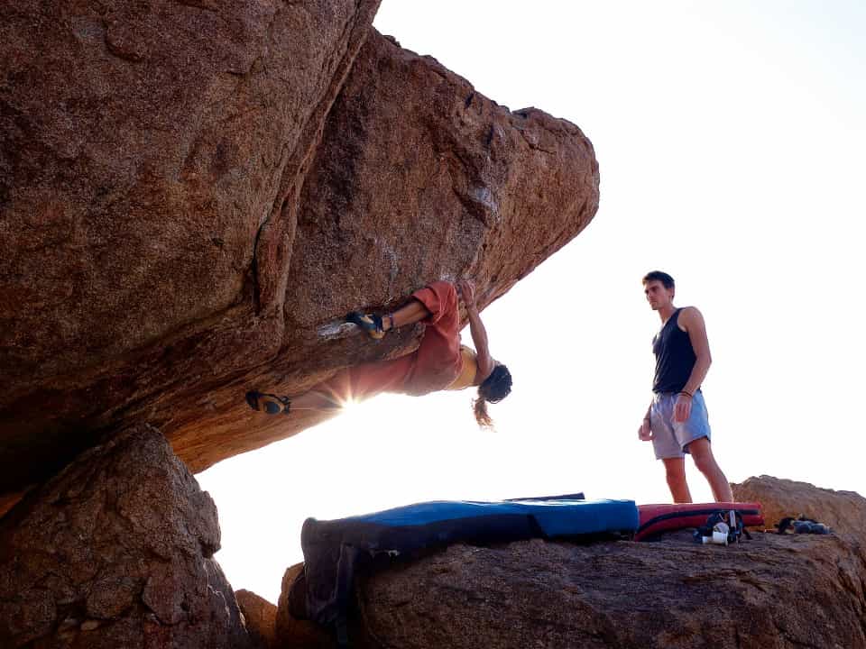 2 people bouldering on red rocks