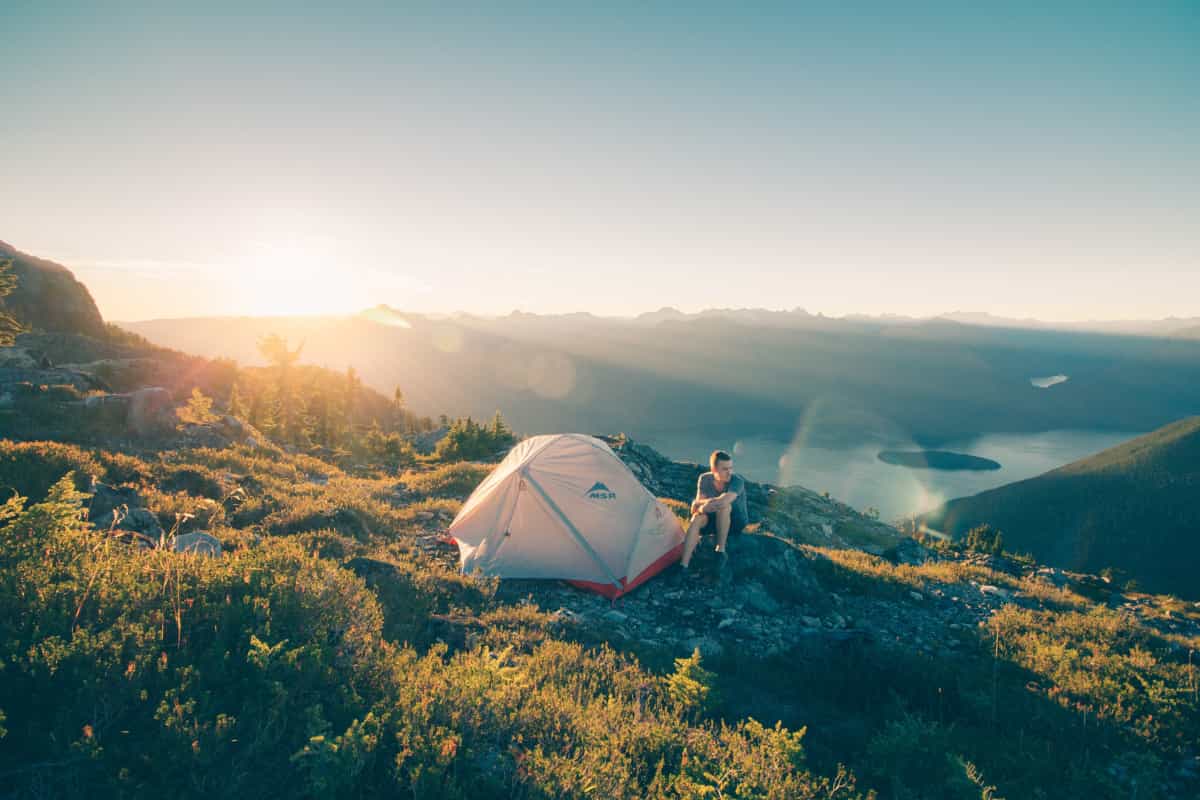 Man sitting next to his lightweight tent (by Glen Jackson on Unsplash)