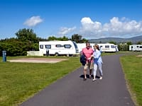 Couple walking through the electric hardstanding touring pitch at Southerness Couple walking through the electric hardstanding touring pitch at Southerness